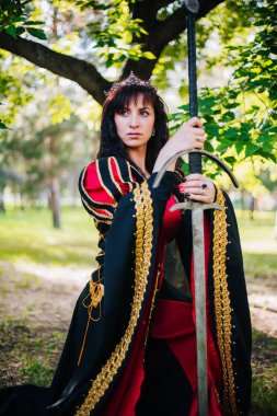 Kraliçe onu elinde bir kılıç ile. Taç güzel kız. Fantezi. Altın nakış ile Ortaçağ siyah ve kırmızı elbise.