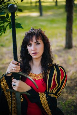 Kraliçe onu elinde bir kılıç ile. Taç güzel kız. Fantezi. Altın nakış ile Ortaçağ siyah ve kırmızı elbise.