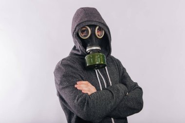A guy in a gas mask and a gray sweatshirt in a hood on a white background. The stink in the toilet. Panic during quarantine. Coronavirus pandemic.