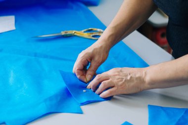 Creating handmade medical masks. Sewing protective masks at home. Cut on the table. The work of a seamstress in quarantine.