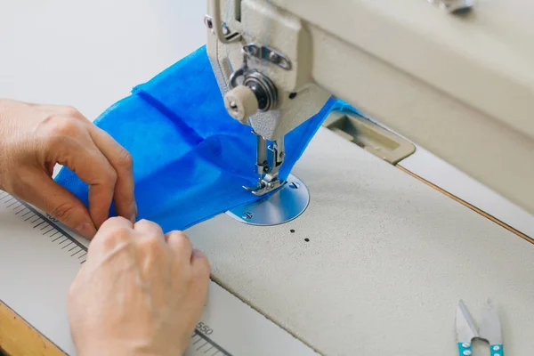 在缝纫机上逐步缝制蓝色面料医用口罩 工业缝纫机的特写使缝合线形成 — 图库照片