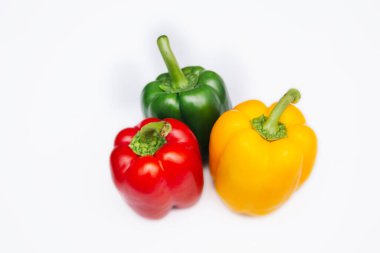 Sweet pepper multicolored on a white background. Red, yellow and green peppers lie on a light table.