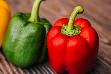 Sweet pepper multicolored on a dark wooden background. Red, yellow and green peppers are on the table.