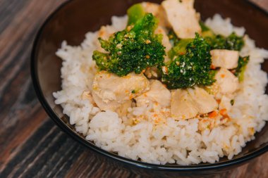 Green cabbage broccoli with rice and white meat. On a dark wooden table.