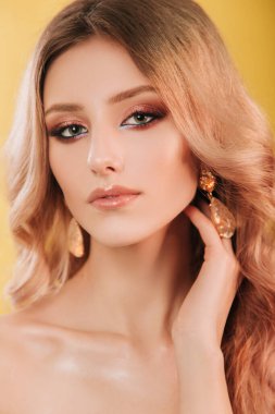 Güzel, genç model sarışın yakın plan portre. Profesyonel makyajlı, saç stili, sarı arka planda stüdyo fotoğrafı olan bir kız. Moda fotoğrafçılığı