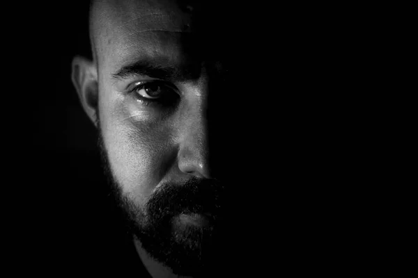 Sakallı genç beyaz bir adamın portresi. Beyaz siyah portre, beyaz bir gencin portresi. Gölgede yarı gizli bir yüz portresi.