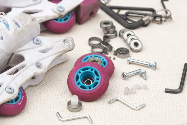 Inline roller skate repair. Roller skate bearing replacement. Disassembled roller skates, new and worn bearings, axles, bushings, screws and hex wrenches.