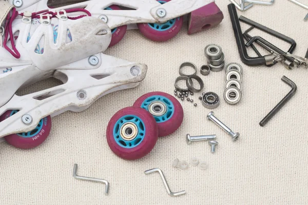 Inline roller skate repair. Roller skate bearing replacement. Disassembled roller skates, new and worn bearings, axles, bushings, screws and hex wrenches.