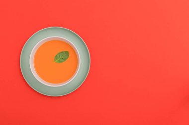Kırmızı arka planda mavi bir tabakta beyaz gazpacho kasesi. Üst Manzara. Boşluğu kopyala.
