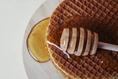 Bal balığı, tahta tepside waffle yığınının üzerine bal döker. Üst görünüm.