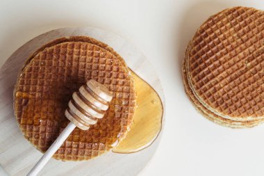 Bal balığı, tahta tepside waffle yığınının üzerine bal döker. Üst görünüm.