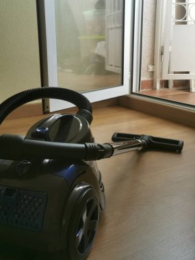 Evde temizlik, balkona açılan bir kapı, elektrik süpürgesi temizleme işlemi.