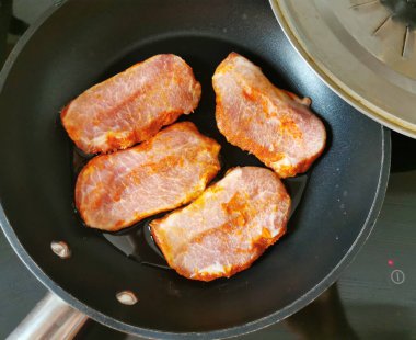 Kızartma tavasında domuz eti ve ocağın kapağı.