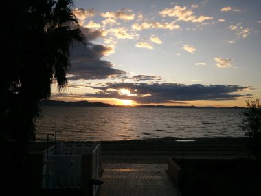 Deniz kıyısında gün batımı kara bulutlarla