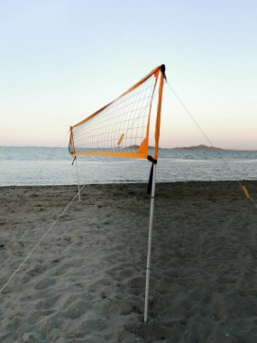 Sakin bir yaz akşamında plajda gün batımına karşı voleybol ağı.
