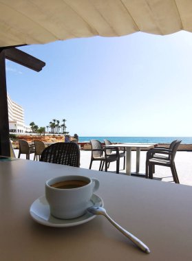 Yazın bir kafede çay tabağı ve kaşıkla bir fincan kahve.