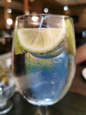 Arka planda bulanık bir bardakta limonlu tonik.