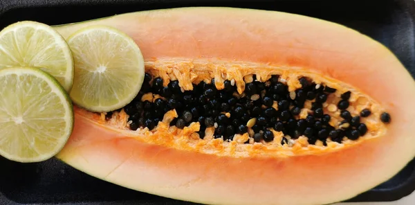 papaya and lime fruit composition on a black background