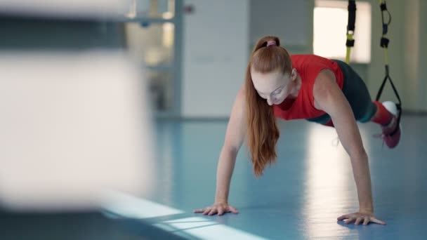 Jonge vrouw doet push-ups op de TRX. — Stockvideo