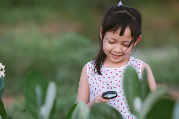 Mutlu Asyalı Küçük Kız Parktaki Yeşil Yaprak Ağacında Büyüteçten Bakıyor — Stok fotoğraf
