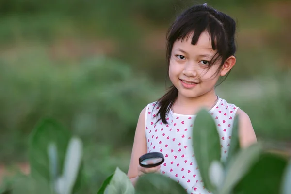 Feliz Niña Asiática Mirando Través Una Lupa Árbol Hojas Verdes — Foto de Stock