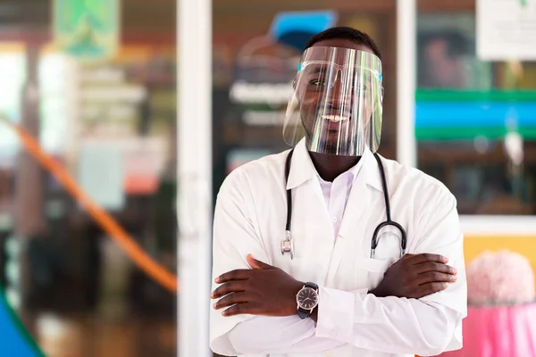 African doctor wear face shield and holding stethoscope with kind and smiling