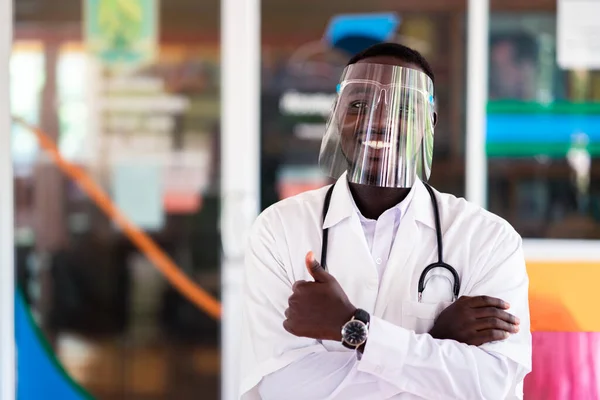 African doctor wear face shield and holding stethoscope with show good sign