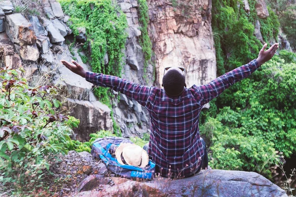 Freedom African traveler  sitting on top of the mountain with backpack and hat