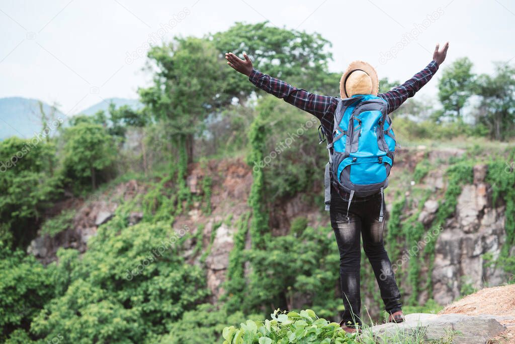 Freedom African traveler  sitting on top of the mountain with backpack and hat