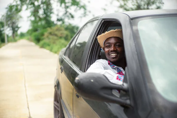 African man driver smiling while sitting in a car with open front window