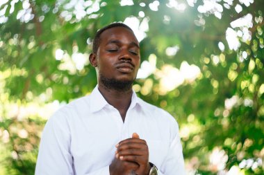 Afrikalı adam yeşil doğada Tanrı 'ya dua ediyor.