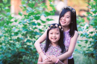 Asyalı anne kızını sevgiyle kucaklıyor. Anneler günü ve aile kavramı.