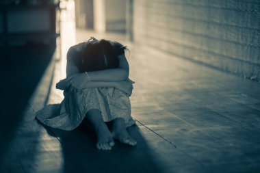 Karanlıkta, depresyonda ve anksiyete bozukluğunun ortasında tek başına oturan üzgün küçük kız.