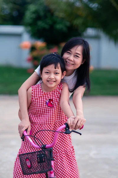 Schöne Asiatische Mutter Unterrichtet Und Umarmt Ihre Tochter Ein Fahrrad — Stockfoto