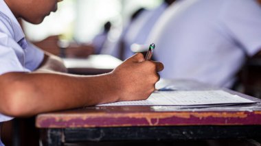 Öğrenciler sınıfta baskı altında yazıyor ve sınava giriyorlar. 16: 9 stili.