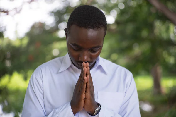 African man praying to god in the green nature