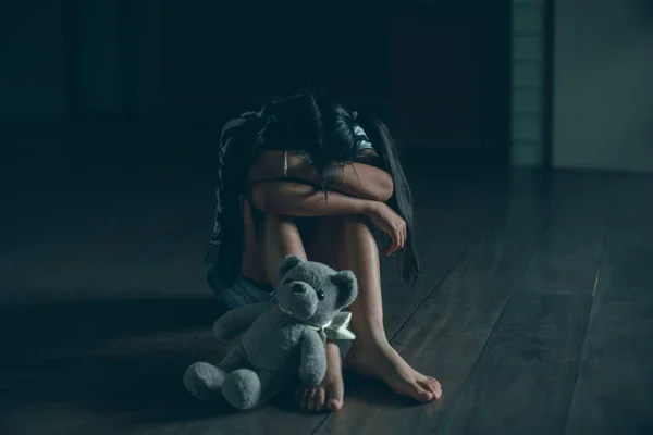 悲しいです小さな子供女の子座っているだけでテディベアで床 — ストック写真
