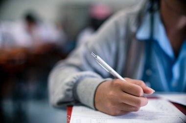 Sınav sorularını yazan ve okuyan öğrenciler, okuldaki sınav kağıtlarını stres ile okuyorlar.