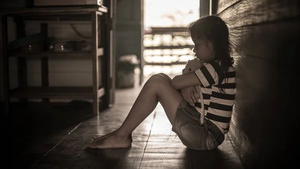 Üzgün küçük kız, yalnız oyuncak ayının yanında oturuyor.