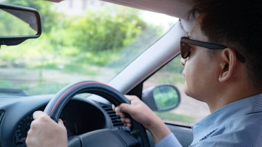 Arabada güneş gözlüklü bir adam var.