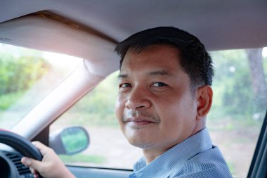 Adam nazikçe arabaya biniyor ve gülümsüyor.