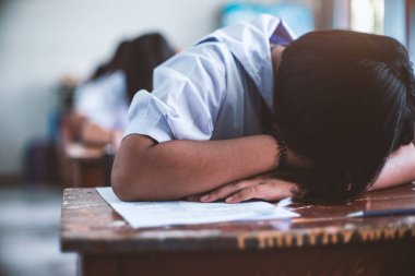 Sınav sınıfında uyuyan yorgun üniformalı öğrenci.