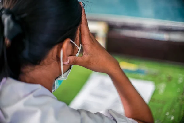 Students wearing mask for protect  corona virus or covid-19 and doing exam answer sheets exercises in classroom of school with stress.