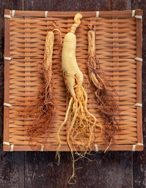 Bambu dokuması üzerine taze ve kuru ginseng ve ahşap zemin üzerinde kopya alanı
