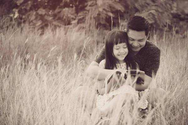 Tipo Asiático Padre Sentado Hierba Con Pequeña Hija Sentada Lectura — Foto de Stock