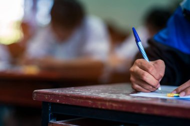 Sınav sorularını yazan ve okuyan öğrenciler, okuldaki sınav kağıtlarını stres ile okuyorlar.