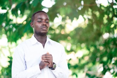 Afrikalı adam yeşil doğada Tanrı 'ya şükretmek için dua ediyor.