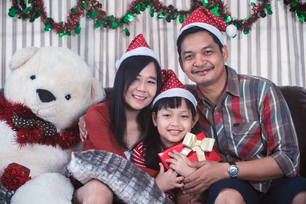 Asian family in Christmas interior.Happy mother father and  daughter holding a gift box with smile