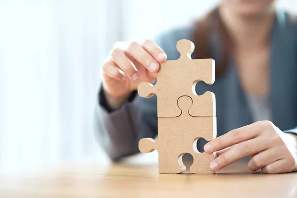 Business solutions partnership and strategy concept, Businesswoman hand connecting jigsaw puzzle on desk.