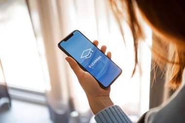 Çevrimiçi eğitim, e-öğrenme. Ekranda yazılı cep telefonu kullanan genç bir kadın e-öğrenme ve kare akademik başlık resmi, uzaklık eğitimi.